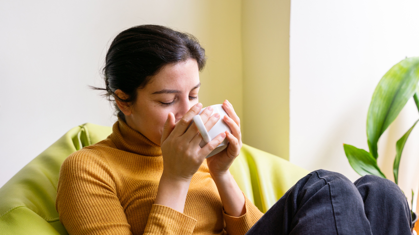 A woman enjoying fresh cup of green tea at her home